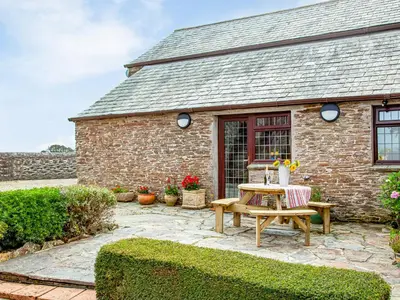 a stone house with a table and chairs in front of it at The Nook in Saint Ewe