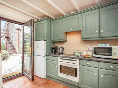 a kitchen with green cabinets and a refrigerator at The Nook in Saint Ewe