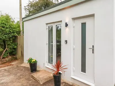 a white garage with a door and two potted plants at Pheasant View in Truro