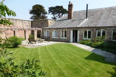 an exterior view of a house with a yard at The Coach House within heritage Tregrehan Garden on Cornwall's South Coast in Carlyon Bay