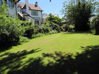 a yard with a large lawn in front of a house at Tregarth House in St Austell