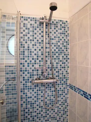 a bathroom with a shower with blue tiles at Tregarth House in St Austell