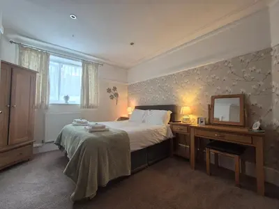 a bedroom with a bed and a dresser and a mirror at Tregarth House in St Austell