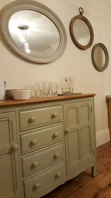 a dresser with glasses on it with a mirror at Schooner Point Guest House in Looe