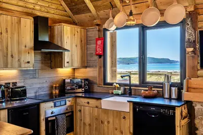 a kitchen with wooden cabinets and a large window at Finest Retreats - Driftwood in Poundstock