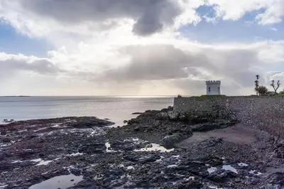 a lighthouse on the shore of a body of water at Room 1, Hotel style double bedroom in Marazion in Marazion