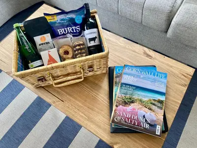 a basket of snacks and a book on a table at Gannets Rest - Spacious Static Caravan with Sea Views in Polperro