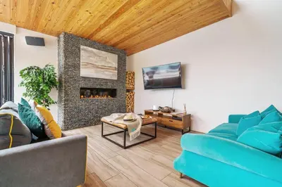 a living room with a blue couch and a fireplace at Award Winning 5* BEACH HOUSE! Hot Tub & Fire Pit in Portreath