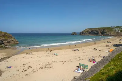 a group of people on a beach near the ocean at Award Winning 5* BEACH HOUSE! Hot Tub & Fire Pit in Portreath