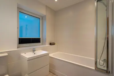 a white bathroom with a sink and a bath tub at Lanyon in St Ives