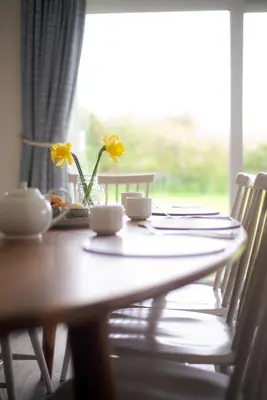 a wooden table with a vase with yellow flowers on it at Trevose Golf and Country Club in Padstow
