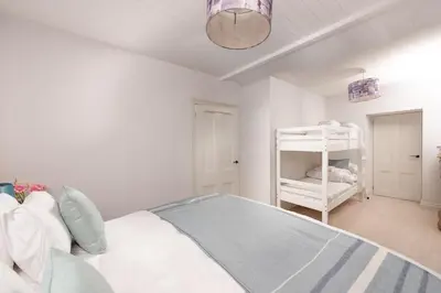 a white bedroom with a bed and a crib at Watersend in Porth
