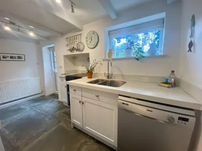 a white kitchen with a sink and a window at Brook Cottage is a traditional fisherman's cottage in Port Isaac