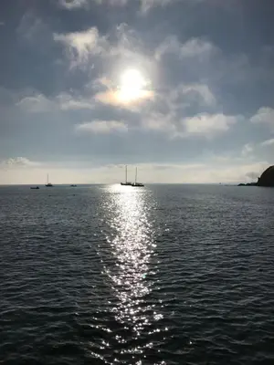 a large body of water with the sun reflecting on the water at Mevagissey Boutique Flatlet with sea and countryside views in Mevagissey