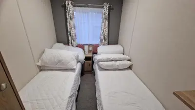 two beds in a small room with a window at Roecliff in St Austell