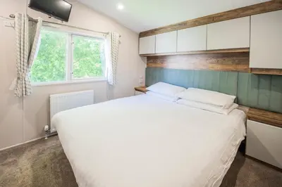 a bedroom with a large white bed and a window at Killigarth Manor Holiday Park in Polperro