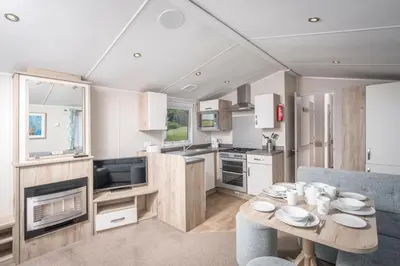 a kitchen and living room with a table and chairs at Killigarth Manor Holiday Park in Polperro