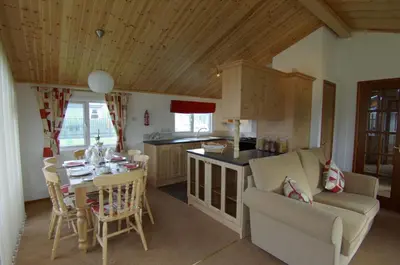 a kitchen and living room with a table and a couch at Killigarth Manor Holiday Park in Polperro