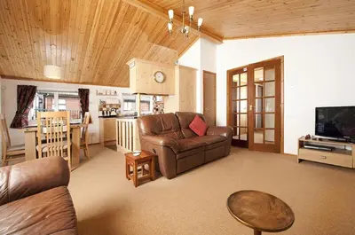a living room with a leather couch and a television at Killigarth Manor Holiday Park in Polperro