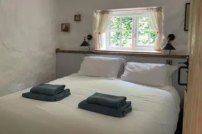 a white bed with two towels on top of it at The Anvil, 2 bed cottage, in the heart of Cornwall in Gwennap