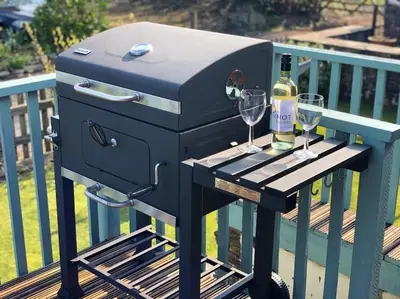 a charcoal grill with two glasses of wine on a deck at The Stables - Crackington Haven Cornwall in Crackington Haven