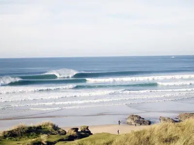 a beach with people walking on the sand and waves at Modern House nr Gwithian Beach & St Ives in Tuckingmill