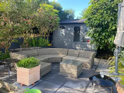 a patio with a couch and tables and trees at An Mordros 15 Polkirt Heights in Mevagissey