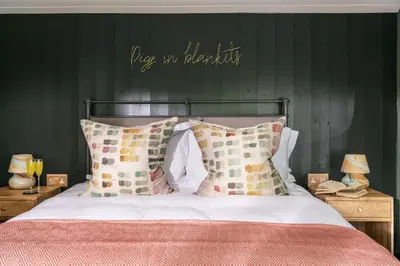 a bedroom with a bed with a green wall at The Pigsty & Spa Garden at Tregoose Old Mill in Newquay