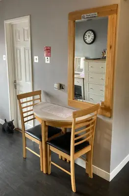 a dining room table with two chairs and a mirror at Twin Gates Annexe in Falmouth