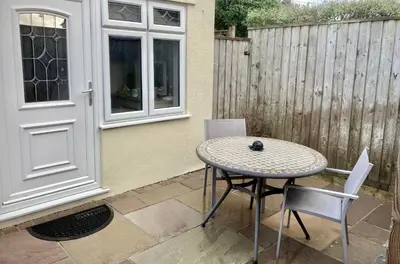 a patio with a table and chairs and a fence at Twin Gates Annexe in Falmouth