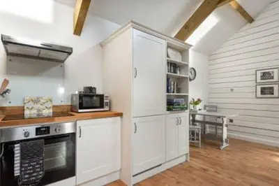 a kitchen with white cabinets and a stove top oven at Gilliflower 1 bedroom cottage at Trethwale Barns Holiday Home in Saint Keyne