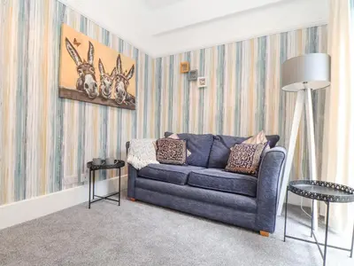 a living room with a blue couch and animals on the wall at Little Polgray in St Austell