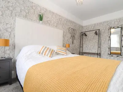 a bedroom with a large bed with a yellow blanket at Little Polgray in St Austell