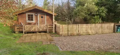 a wooden cabin with a fence and a gate at Polgwedhen Lodge in Truro