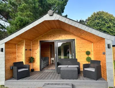 a small shed with chairs and a table on a deck at Riverside Retreats - Steamers Meadow in Gwinear