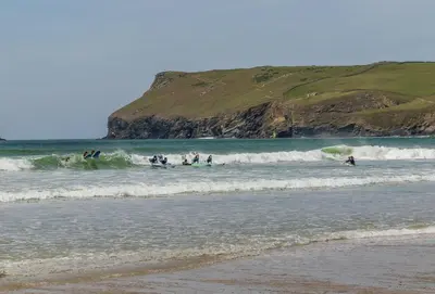 a group of people playing in the waves in the ocean at April Cottage in Polzeath