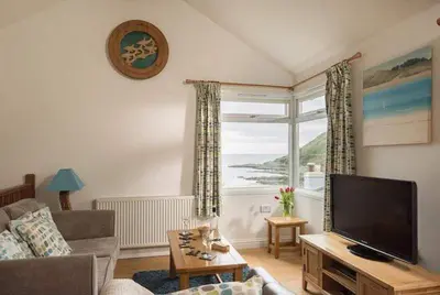 a living room with a television and a large window at Cosy Beachfront Retreat with Stunning Sea Views & Free Access to a Local Indoor Pool in Talland