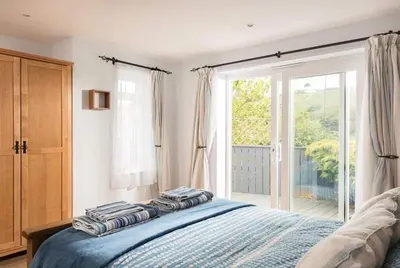 a bedroom with a bed and a large window at Cosy Beachfront Retreat with Stunning Sea Views & Free Access to a Local Indoor Pool in Talland
