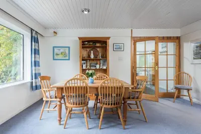 a dining room with a wooden table and chairs at Stunning River Views, Tranquil Split-Level House, Private Garden & Parking in Golant