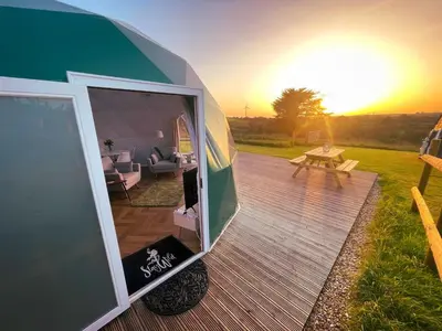 a small caravan with a living room and a table at Sunset Ridge - Luxury Geodesic Dome set in the beautiful countryside in Porkellis