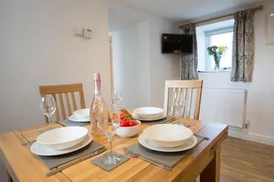 a wooden table with plates and wine glasses on it at Cornish Views in Camborne