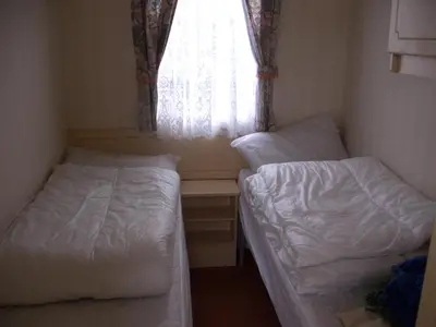 two beds in a small room with a window at Colin and annioes caeravan in Looe