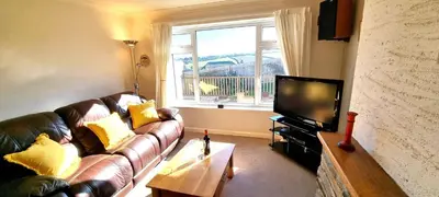 a living room with a leather couch and a television at Trenare in Perranporth