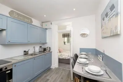 a kitchen with blue cabinets and a table with plates on it at Rame in Looe