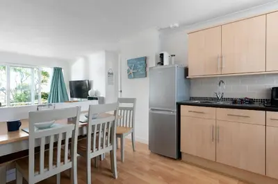 a kitchen and dining room with a table and a refrigerator at 3 Europa Court in Mawgan Porth in Mawgan Porth