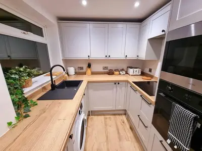 a kitchen with white cabinets and a washer and dryer at 1Rosemount -Marazion - Iconic view of St Michaels Mt, Sea, Beach, 2xParking, Netflix Prime in Marazion