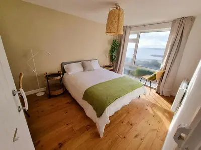 a bedroom with a large bed and a large window at 1Rosemount -Marazion - Iconic view of St Michaels Mt, Sea, Beach, 2xParking, Netflix Prime in Marazion