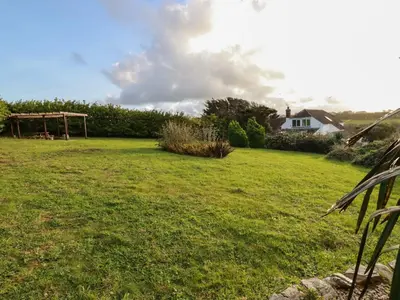 a field of grass with a house in the background at Little Seacroft in Newquay