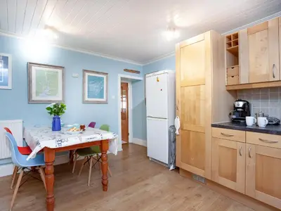 a kitchen with a table and chairs and a refrigerator at Tean in Polruan