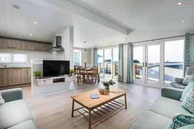 a living room with a couch and a tv at Gull Rocks Beach Lodges in Cubert